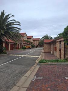 an empty street in a residential neighborhood with houses at Notre Petit Paradis in Mossel Bay