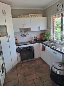 a kitchen with white cabinets and a sink at Notre Petit Paradis in Mossel Bay