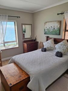 a bedroom with a large bed and a window at Notre Petit Paradis in Mossel Bay