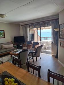 a living room with a couch and a table and chairs at Notre Petit Paradis in Mossel Bay