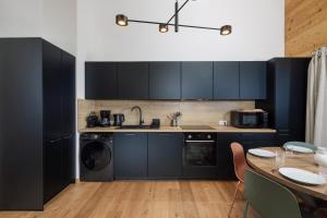 a kitchen with dark blue cabinets and a table at Alpium, Morzine centre, 5 personnes in Morzine +3 photos