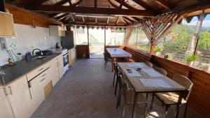 a kitchen with tables and chairs in a room with windows at Casa NICORAD Camere in Pucioasa