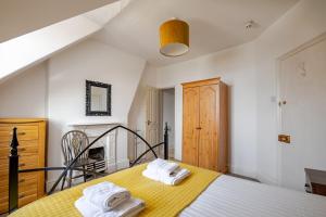 ein Schlafzimmer mit einem gelben Bett mit Handtüchern darauf in der Unterkunft Victorian Cartref in the heart of Llandudno in Llandudno