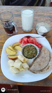 Un plato de comida con fruta y guacamole en una mesa. en Purnata Farm and Arts Residency, en Pokhara