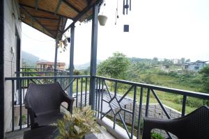a balcony with two chairs and a view at Jags-N-Kals in Bhīm Tāl