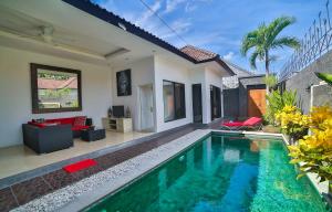 a villa with a swimming pool in front of a house at Bali Cinta Villa in Seminyak