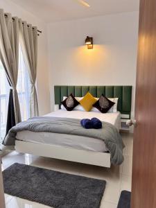 a bedroom with a bed with a green headboard and pillows at Nest Quest Amoret Homes Resort style 1Bhk Adora De Goa in Dabolim +7 photos