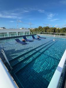 a large swimming pool with blue chairs in the water at Flat Novo no Centro de Porto de Galinhas in Porto De Galinhas