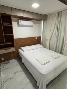 a bedroom with a white bed and a window at Flat Novo no Centro de Porto de Galinhas in Porto De Galinhas