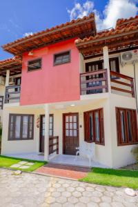 a red and white house with a bench in front of it at Apart perto da praia in Porto Seguro