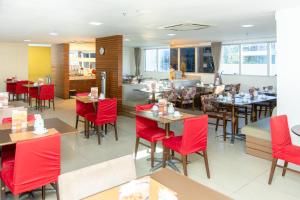 a dining room with red chairs and tables at Salvador Business by Avectur in Salvador