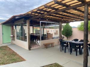 a patio with tables and chairs under a wooden pergola at Pousada Recanto Flor da Serra in São Roque de Minas