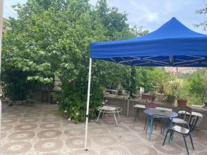 a blue umbrella on a patio with chairs and tables at Duplexe familiale avec jardin in Hamma Bouziane
