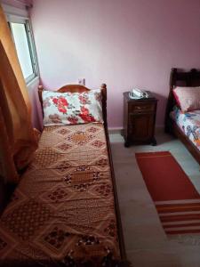 a small bedroom with a bed and a table at Duplexe familiale avec jardin in Hamma Bouziane