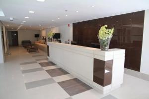 a lobby with a reception counter with a vase of flowers at Salvador Business by Avectur in Salvador +40 photos