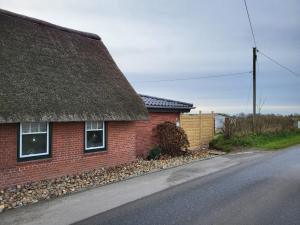 a brick house with a thatched roof on a street at Gemütliche Ferienwohnung unter Reet in Ahrenshöft