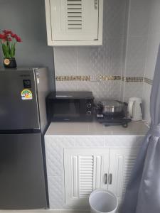 a small kitchen with a microwave and a refrigerator at Nirun Condo Pattaya in Ban Nong Chaeng