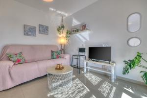 a living room with a pink couch and a tv at The mermaid House- Playa Honda in Playa Honda