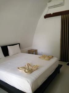 een slaapkamer met een wit bed en 2 handdoeken bij Sapari's Family in Gili Air