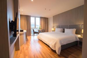 a bedroom with a large bed and a desk and a table at New Season Square Hotel in Hat Yai +41 photos