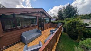 a large wooden deck with two blue chairs on it at IVY Cabin in Trawsfynydd