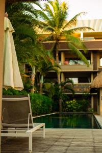 una sedia e un ombrellone accanto alla piscina di Appartement de Luxe au Domaine des Alizées Club & Spa, Grand Baie a Grand Baie