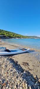 a surfboard sitting on a beach next to the water at Apartment Karuza Rukavac in Vis