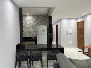 a kitchen with a black table and chairs and a refrigerator at Apartamento novinho e central - 2 ou 3 quartos, 2 banheiros, elevador e estacionamento in João Monlevade