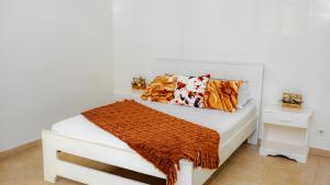 a bedroom with a white bed with a orange blanket at Keur Maï in Dakar
