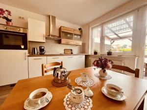una cucina con tavolo in legno con tazze e piattini di NEU! Ferienwohnung Tant Anni mit Saunaoption a Ihlow