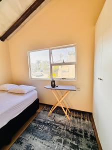 Un dormitorio con una cama y una mesa y una ventana. en Balcony Bliss, en Johannesburgo
