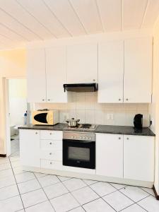 Una cocina con gabinetes blancos y un horno de estufa. en Balcony Bliss, en Johannesburgo