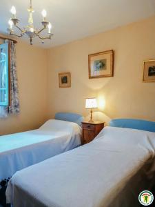 a room with two beds and a table with a lamp at Au village in Boutx +7 photos