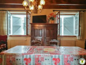 a dining room with a table and a tv and windows at Au village in Boutx