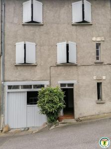a building with two white garage doors and a plant at Au village in Boutx