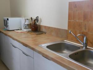 a kitchen counter with a sink and a microwave at Au village in Boutx