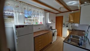 a kitchen with a white refrigerator and some windows at Apartment in peacefull surroundings in Ådnavik