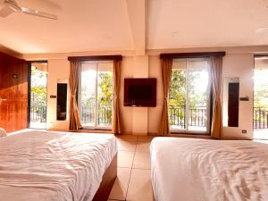 a bedroom with two beds and a flat screen tv at Unwind Karjat in Palasdhari +60 photos