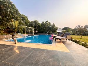 a swimming pool with two chairs and a table next to it at Unwind Karjat in Palasdhari