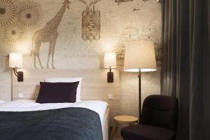 a bedroom with a bed and a chair and a wall at Scandic Aalborg Øst in Aalborg