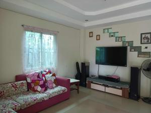 a living room with a couch and a flat screen tv at Joel's House in Iloilo City