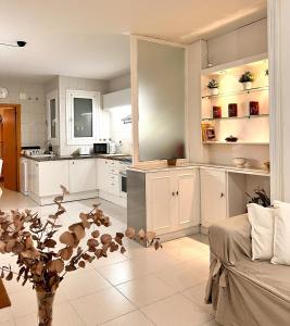 una cocina con armarios blancos y un jarrón con una planta en Acojedor apartmento, centro con patio, en Sabadell