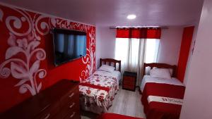 a red room with two beds and a tv at Hotel D'Gloria Churin in Churín