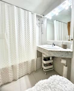 Un baño con lavabo y cortina de ducha. en Acojedor apartmento, centro con patio, en Sabadell