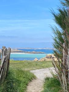 a path to a beach with the ocean in the background at Villa Les Pieds dans l'Eau et sans canicule ! in Santec