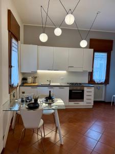 Una cocina con gabinetes blancos y una mesa y sillas. en Vicenza Charm Apartment, en Vicenza