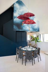 a dining room with a table with chairs and red umbrellas at Villa 4 étoiles en bord de mer - Insolite et Dépaysante in Saint-Jacut-de-la-Mer