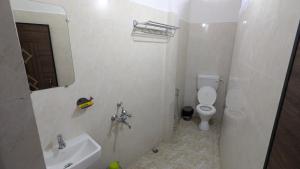 a white bathroom with a sink and a toilet at Kamakhya Homestay by Bonoriya in Guwahati