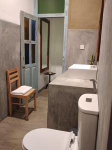a bathroom with a toilet and a sink and a chair at Inura Villa in Ambalangoda