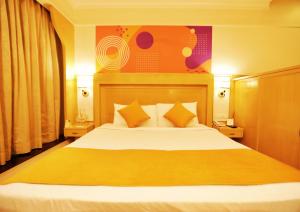 1 dormitorio con 1 cama grande con sábanas amarillas y naranjas en Ira Navi Mumbai, en Kālaj